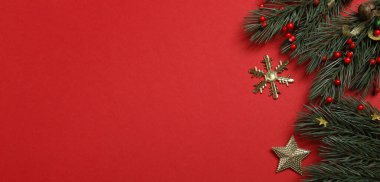 Yılbaşı geçmişi. Kırmızı arka planda köknar dalları ve süslemeler. Üst Manzara. Boşluğu kopyala.