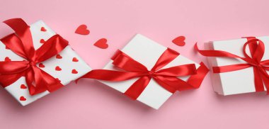 Sevgililer günü hediye kutularında kurdele ve pembe arka planda kalpler var. Üst Manzara. Boşluğu kopyala