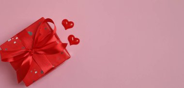 Kalpli ve kurdeleli pembe arka planda hediye kutusu. Sevgililer Günü konsepti.