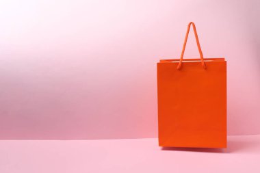 Turuncu arka planda pembe saplı kırmızı alışveriş çantası.
