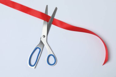 Beyaz arka planda kırmızı kurdele ve makas, düz tasarım. Metin için yer.