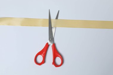 Beyaz arka planda altın kurdele ve makas, düz tasarım. Metin için yer.