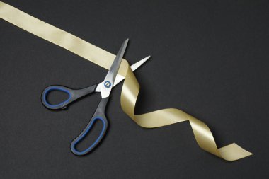 Siyah arka planda altın kurdele ve makas, düz tasarım. Metin için yer.