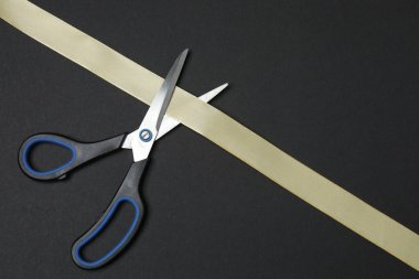 Siyah arka planda altın kurdele ve makas, düz tasarım. Metin için yer.