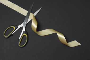 Siyah arka planda altın kurdele ve makas, düz tasarım. Metin için yer.