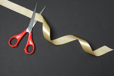 Siyah arka planda altın kurdele ve makas, düz tasarım. Metin için yer.