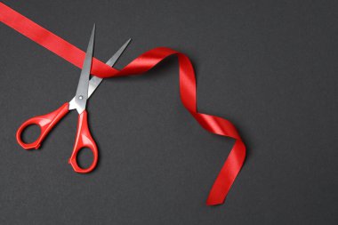 Siyah arka planda kırmızı kurdele ve makas, düz tasarım. Metin için yer.