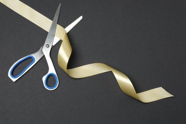 Siyah arka planda altın kurdele ve makas, düz tasarım. Metin için yer.