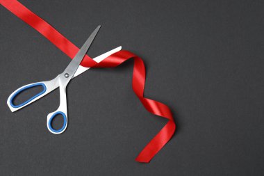 Siyah arka planda kırmızı kurdele ve makas, düz tasarım. Metin için yer.