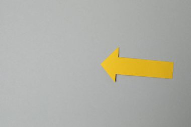 Gri arka planda sarı kağıt ok. İş konsepti.