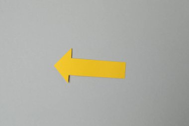 Gri arka planda sarı kağıt ok. İş konsepti.