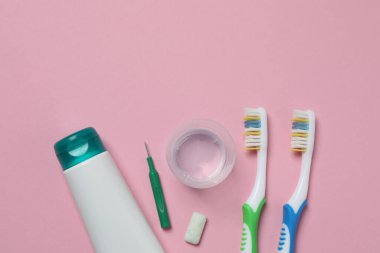 Diş fırçası ve diş macunu, pembe arka planda gargara. Diş bakımı.