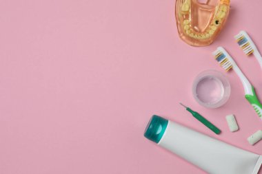 Diş fırçası ve diş macunu, pembe arka planda gargara. Diş bakımı.