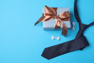 Babalar Günü. Mavi arka planda hediye kutusu, bardak, kahve ve kravat olan kompozisyon.