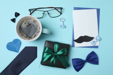 Babalar Günü. Mavi arka planda hediye kutusu, bardak, kahve ve kravat olan kompozisyon.