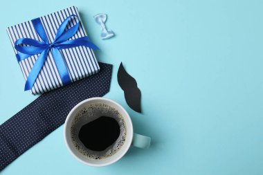 Babalar Günü. Mavi arka planda hediye kutusu, bardak, kahve ve kravat olan kompozisyon.