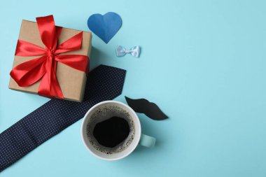 Babalar Günü. Mavi arka planda hediye kutusu, bardak, kahve ve kravat olan kompozisyon.