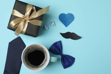 Babalar Günü. Mavi arka planda hediye kutusu, bardak, kahve ve kravat olan kompozisyon.