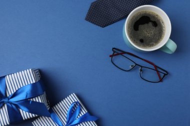 Babalar Günü. Hediye kutusu, bardak, kahve fincanı ve koyu mavi arka planda kravat..