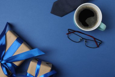 Babalar Günü. Hediye kutusu, bardak, kahve fincanı ve koyu mavi arka planda kravat..