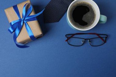 Babalar Günü. Hediye kutusu, bardak, kahve fincanı ve koyu mavi arka planda kravat..