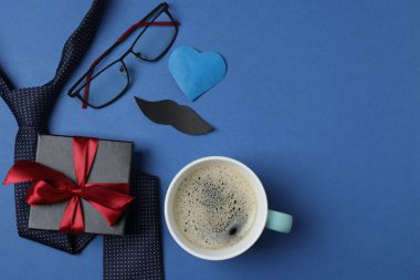 Babalar Günü. Hediye kutusu, bardak, kahve fincanı ve koyu mavi arka planda kravat..