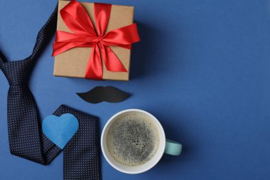 Babalar Günü. Hediye kutusu, bardak, kahve fincanı ve koyu mavi arka planda kravat..