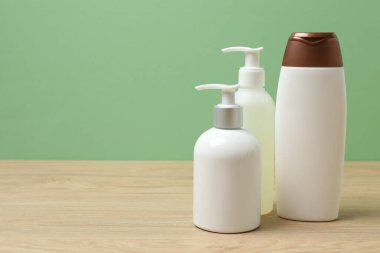 Ahşap bir masada yeşil arka planı olan beyaz tuvalet malzemeleri.