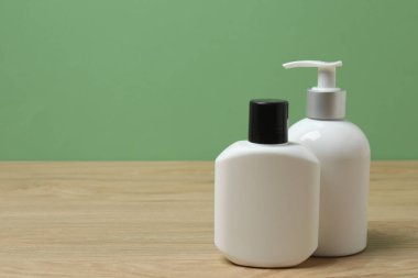 Ahşap bir masada yeşil arka planı olan beyaz tuvalet malzemeleri.