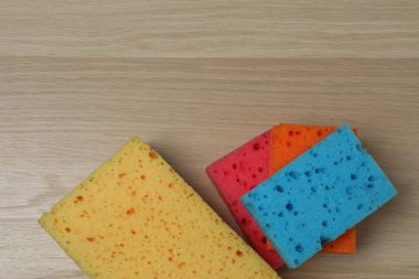 Tahta bir arka planda temizlik ürünü, sünger, eldivenler.