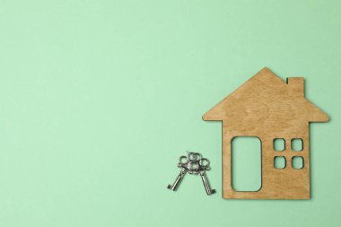 Ahşap ev, insanlar, yeşil arka planda anahtarlar.