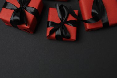Siyah arkaplanda siyah kurdeleli kırmızı hediye kutuları