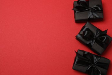 Kırmızı arka planda siyah kurdeleli siyah hediye kutuları
