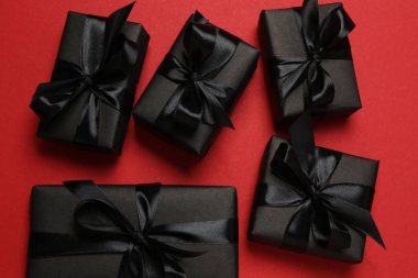 Kırmızı arka planda siyah kurdeleli siyah hediye kutuları