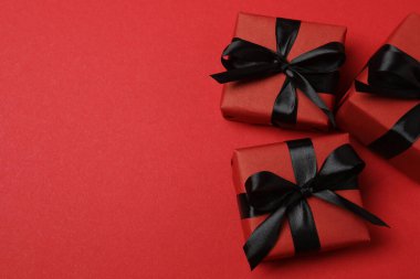 Kırmızı arka planda siyah kurdeleli siyah hediye kutuları