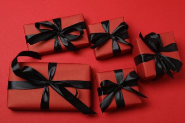 Kırmızı arka planda siyah kurdeleli siyah hediye kutuları