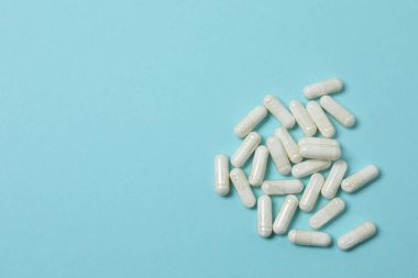 Mavi arka planda vitamin hapları ve şişe, üst manzara. Metin için boşluk