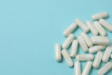 Mavi arka planda vitamin hapları ve şişe, üst manzara. Metin için boşluk