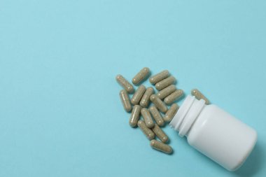 Mavi arka planda vitamin hapları ve şişe, üst manzara. Metin için boşluk