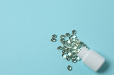 Mavi arka planda vitamin hapları ve şişe, üst manzara. Metin için boşluk