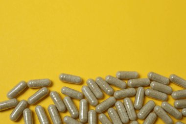 Sarı arka planda vitamin hapları ve şişe, üst manzara. Metin için boşluk