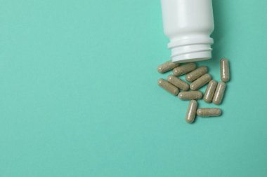 Yeşil arka planda vitamin hapları ve şişe, üst manzara. Metin için boşluk