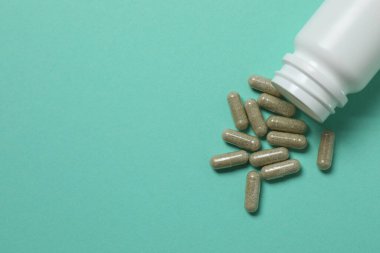 Yeşil arka planda vitamin hapları ve şişe, üst manzara. Metin için boşluk