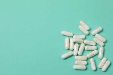 Yeşil arka planda vitamin hapları ve şişe, üst manzara. Metin için boşluk