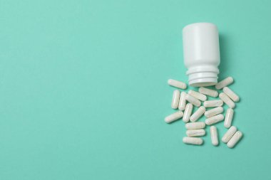 Yeşil arka planda vitamin hapları ve şişe, üst manzara. Metin için boşluk