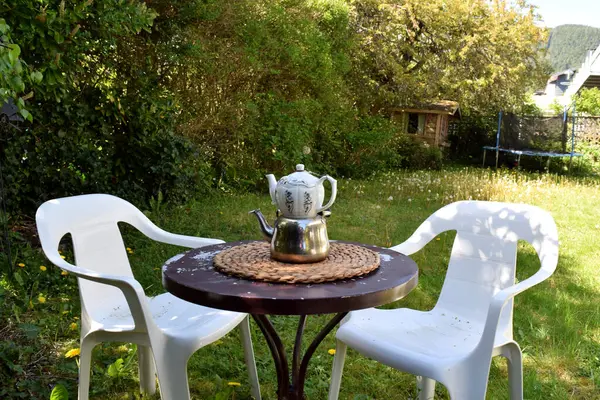 Yeşilliklerle çevrili kırsal bir masada güzel dizayn edilmiş bir çaydanlık sunan büyüleyici bir bahçe çay seti, barışçıl bir açık hava inzivası sunuyor..
