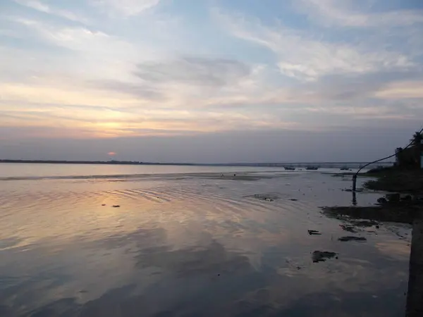           Gökyüzünde yumuşak renklere sahip güzel bir günbatımı geniş bir nehir veya gölün pürüzsüz yüzeyine yansıyarak huzurlu ve atmosferik bir manzara yaratır..