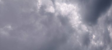 Gri bulutların çeşitli gölgeleriyle dramatik bulutlu bir gökyüzü ve kırılan güneş ışığı parçalarıyla bulutlu ya da fırtınalı bir günün havasını yakalıyor..