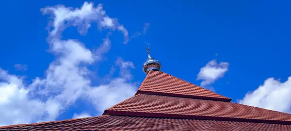 Parlak gümüş bir kubbeyle kaplı kırmızı kiremitli binaların alçak açılı fotoğrafı dağınık beyaz bulutlarla dolu, mavi gökyüzüne karşı kurulmuş..