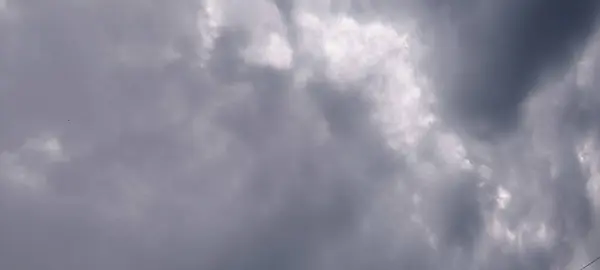 Gri bulutların çeşitli gölgeleriyle dramatik bulutlu bir gökyüzü ve kırılan güneş ışığı parçalarıyla bulutlu ya da fırtınalı bir günün havasını yakalıyor..